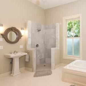 This is a picture of a clean bathroom sink, shower and tub with a window looking outside